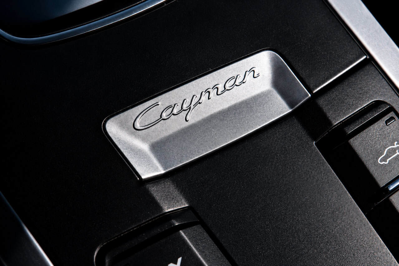 Close-up of the Porsche Cayman interior badge, highlighting the premium detailing of the sports car available for rental in Tenerife.