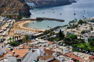 Panoramisch uitzicht op Puerto de Mogán met zijn strand, jachthaven, witgekalkte huizen en vulkanische kustlijn tijdens de dagtour over het eiland Gran Canaria.