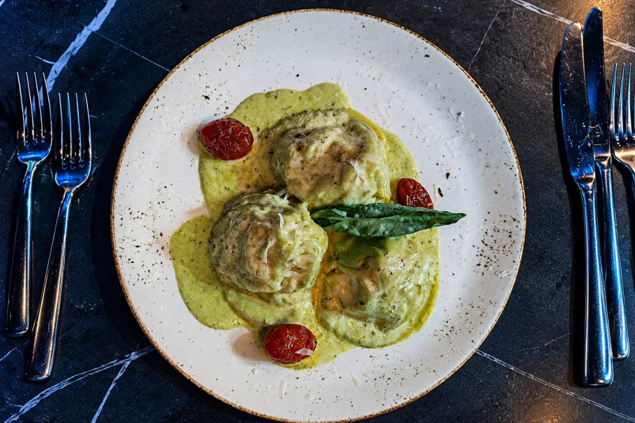 Gourmet ravioli served with creamy herb sauce, roasted tomatoes and fresh basil during a dining experience at nomad show Gran Canaria