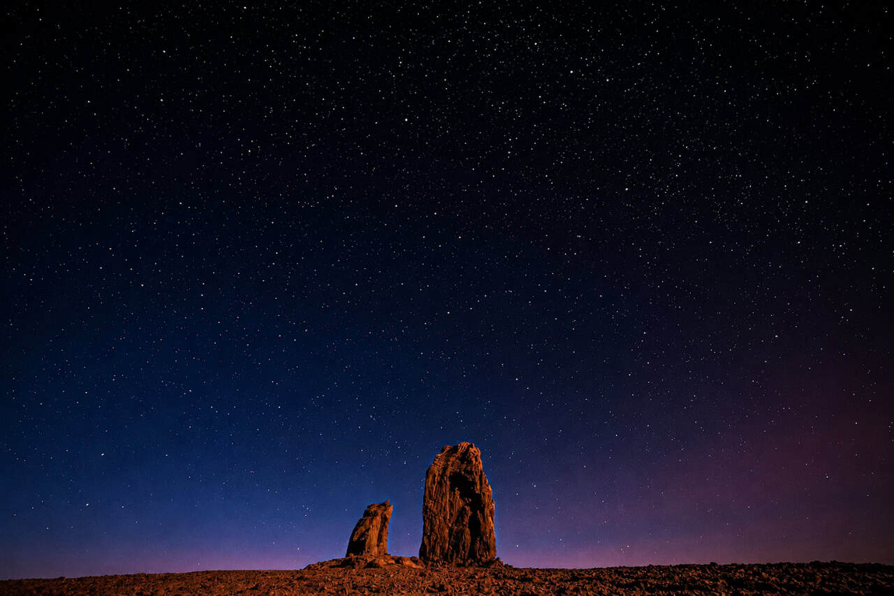 Star-filled sky above volcanic rock formations at night