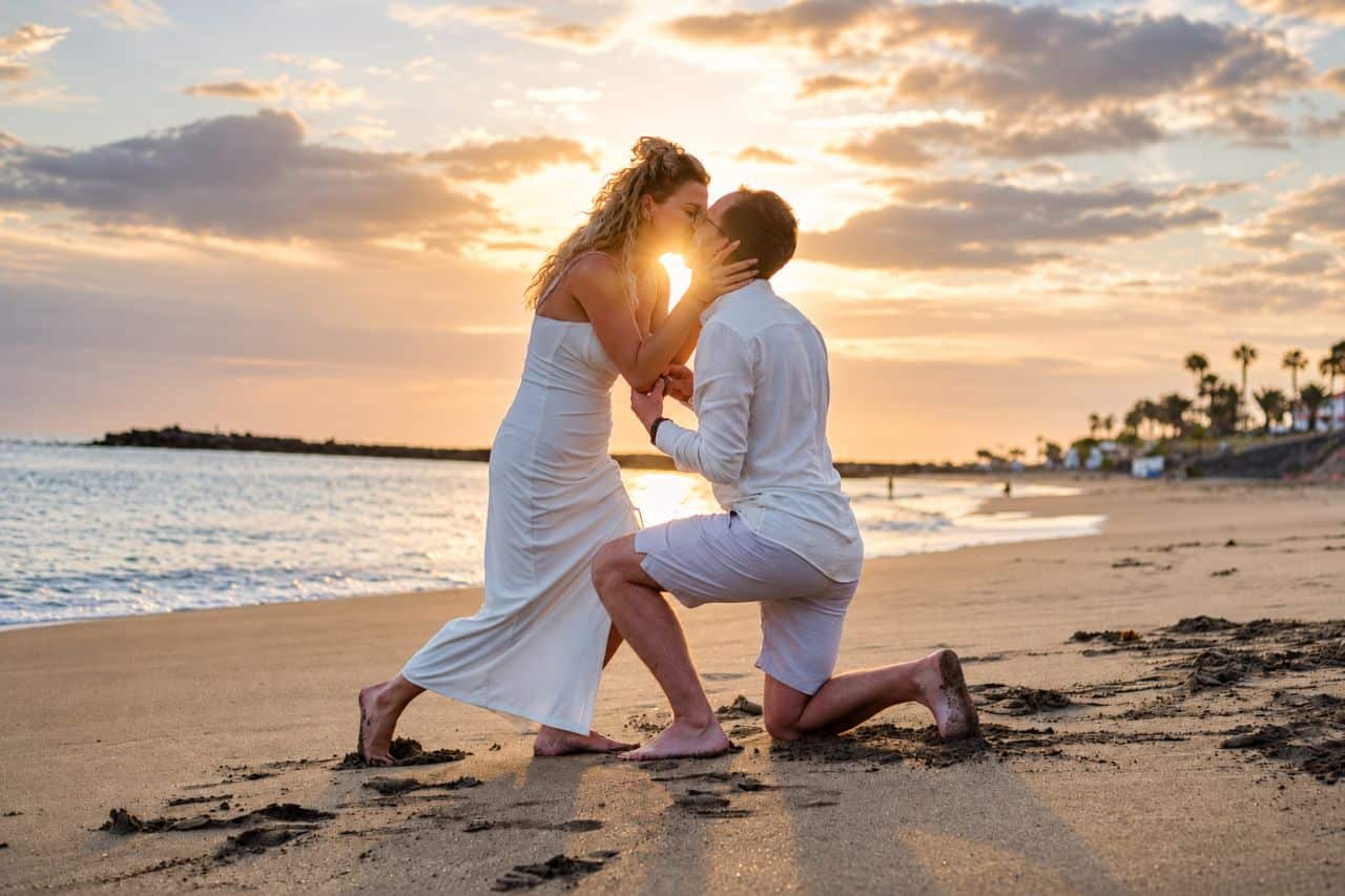 Pasgetrouw stel dat tijdens een sunset-proposeerfeestje op Tenerife Playa del Duque zoenen