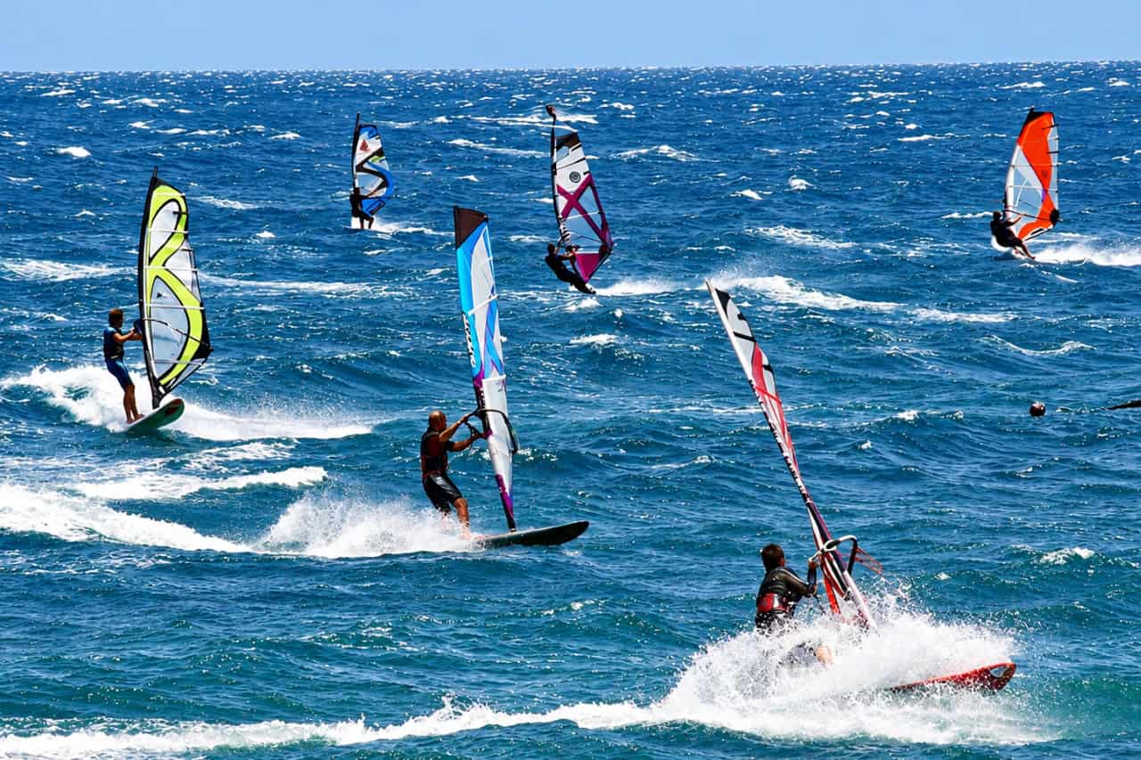Several windsurfers crossing choppy Atlantic waves at El Médano on a windy day