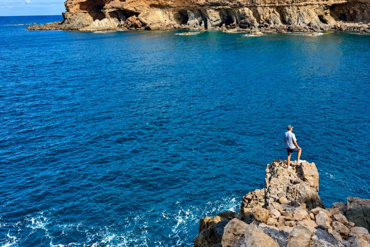 L'artwork delle carte collezionabili Private Loop, ospitata su una roccia sopra il mare blu intenso vicino a Ajuy