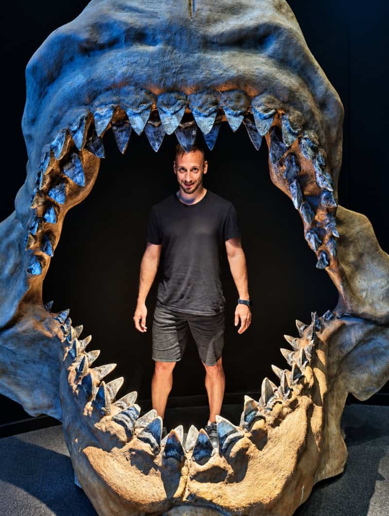 A visitor standing inside a set of giant prehistoric shark jaws at the photo spot in Poema del Mar, Gran Canaria