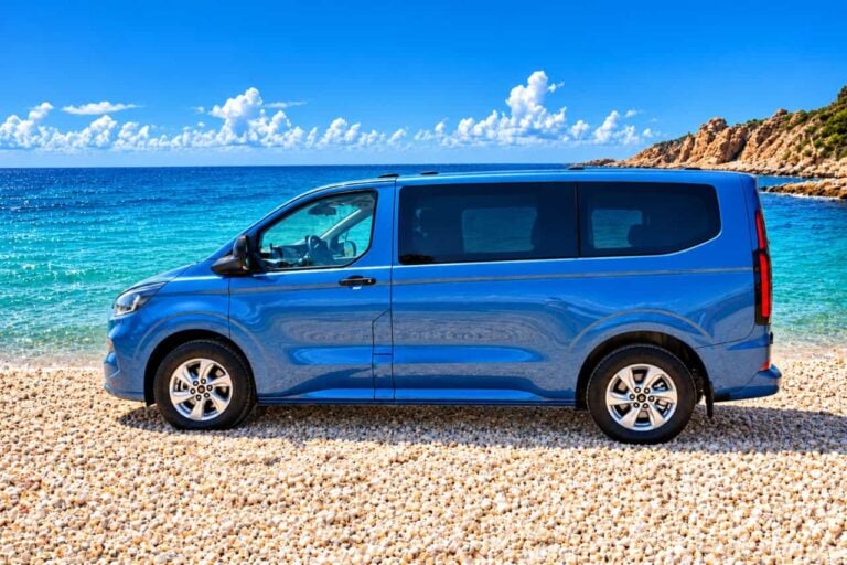 Minibus ibrido blu per il tour privato dell'isola di Fuerteventura, parcheggiato su una spiaggia di ciottoli